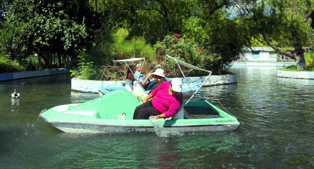Una adulta mayor jugando con el agua desde su bote a pedal.
